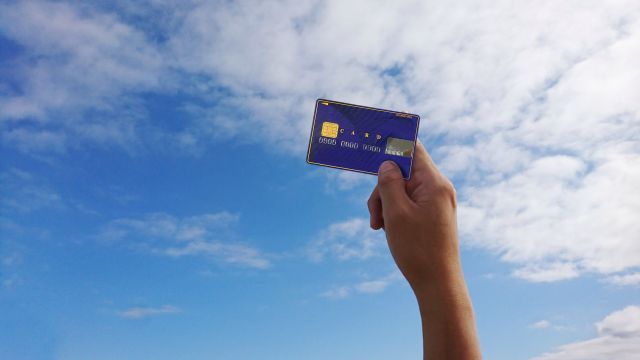 青空に掲げる青いクレジットカード