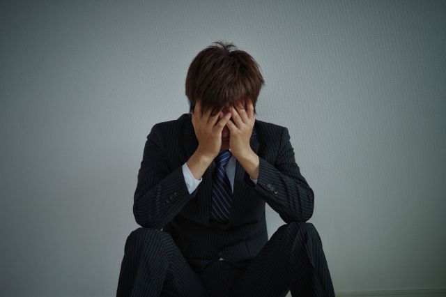 暗い中で頭を抱える男性