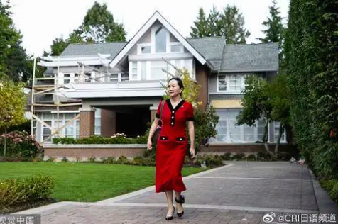 白い家の前を歩く赤服を着た女性