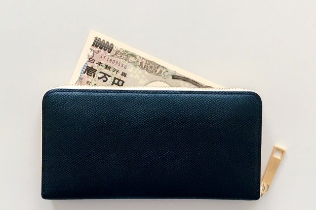 1万円札が飛び出している黒い財布