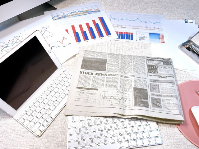 机の上に置かれたパソコンと新聞と資料