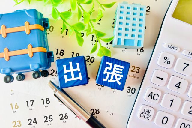 出張と書かれたサイコロと電卓