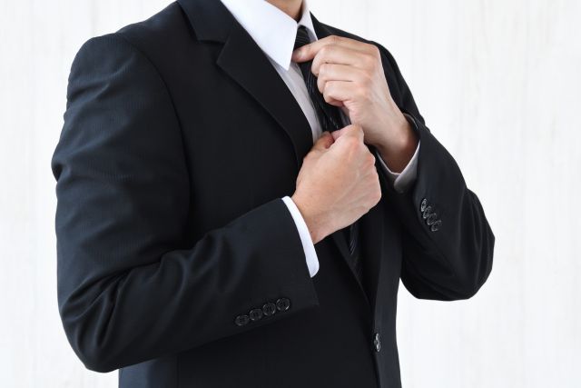 ネクタイを整えるスーツの男性