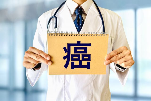 癌と書かれた画用紙を持つ医師