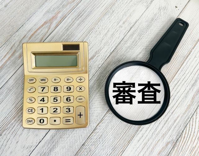 審査の文字を見る娘金と金色の電卓