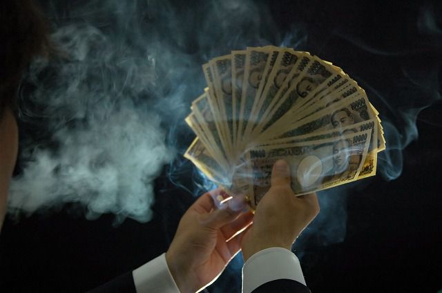 タバコの煙いを吹かしながらお金を数える男性