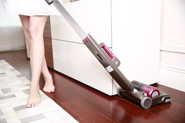 コードレス掃除機で掃除するミニスカートの女性