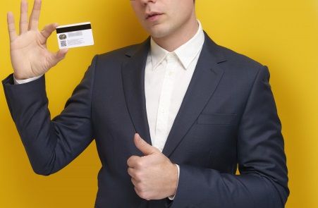 クレジットカードの裏面を見せるスーツ姿の男性