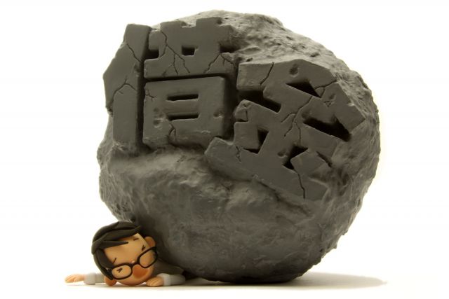 借金と書かれた岩に潰される男性