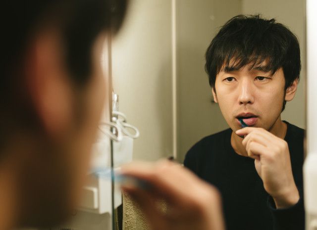 鏡を見ながら歯磨きをする男性