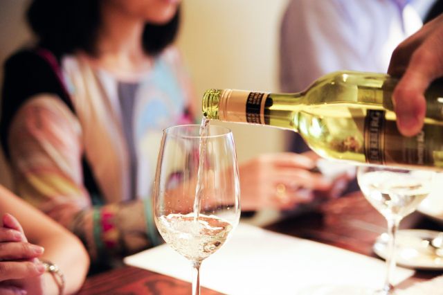 飲み会の会場にてグラスに注がれる白ワイン