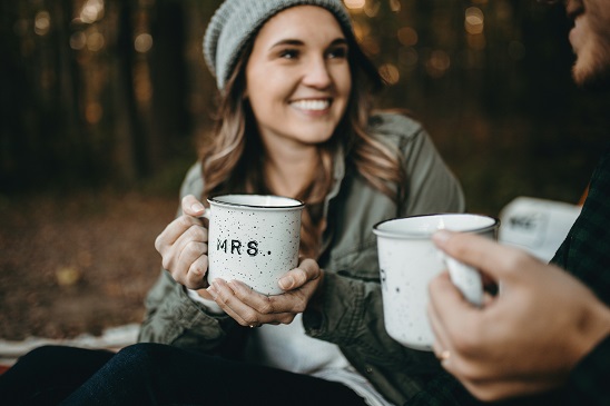 森の中でコーヒーカップを持って笑う若い女性