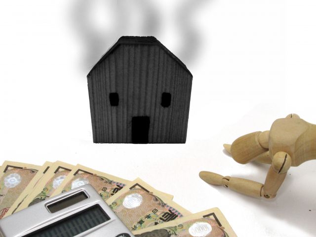 燃えた家の模型とお金と人形
