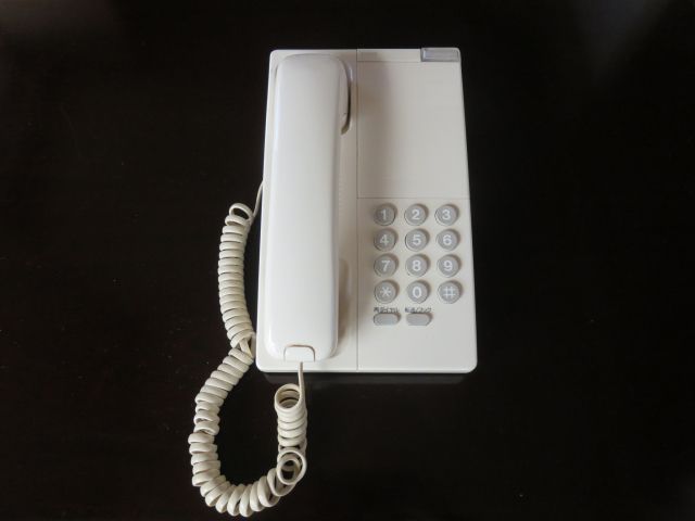 黒いテーブルに置かれた白い固定電話