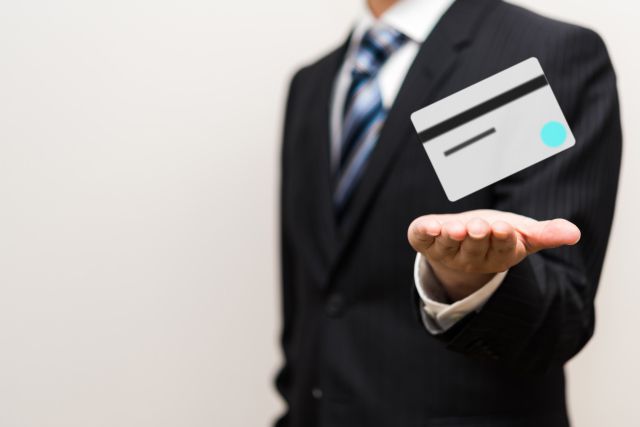 スーツ姿の男性の手の上から浮くクレジットカード