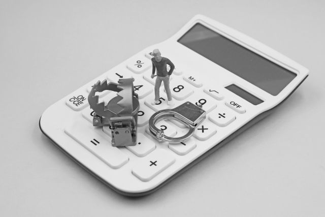電卓の上の手錠と人形と罠