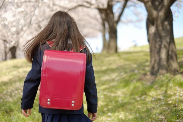 桜並木を歩く赤いランドセルを背負った女の子