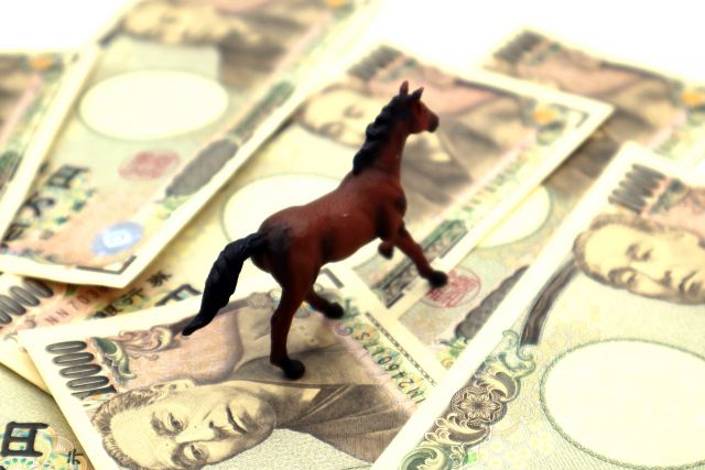 お金の上に置かれた馬の人形