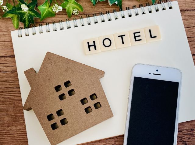 画用紙に書かれたHOTELの文字とスマホと家の模型