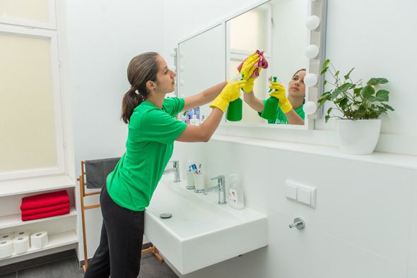 洗面台の鏡を掃除するハウスクリーニングの女性