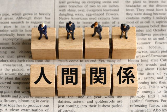新聞の上に置かれた人間関係と書かれたブロックと人形