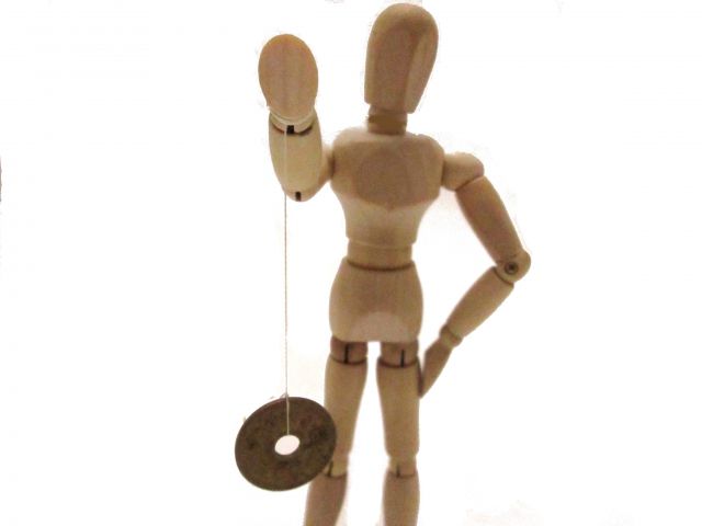5円玉の振り子を持つ人形