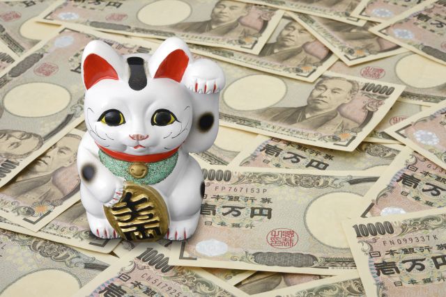 散らばった1万円札の上に置かれた招き猫