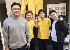 お店の前で写真を撮る4人の男性