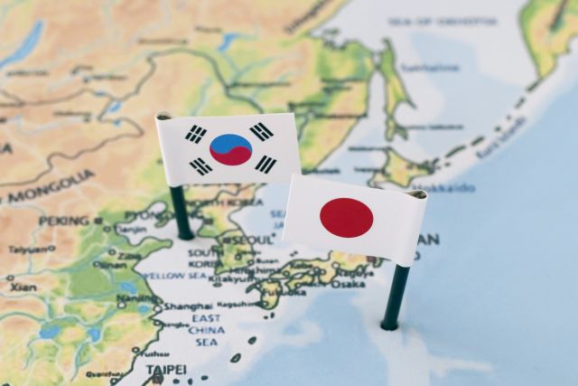 地図の上に立った韓国と日本の国旗