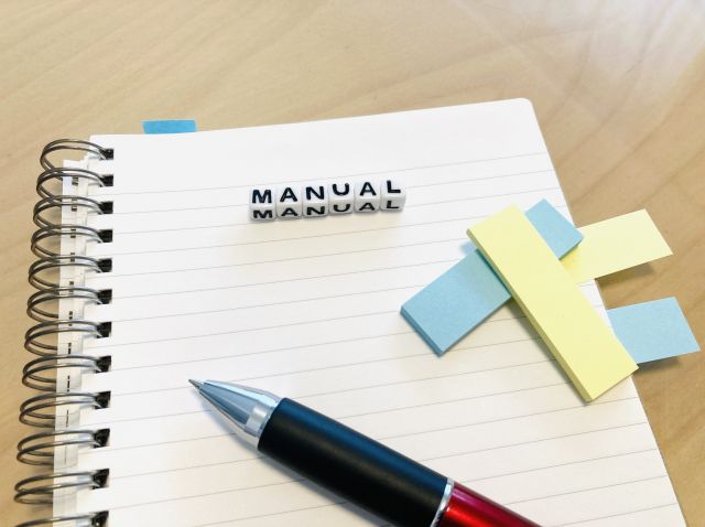 ノートの上に置かれたペンとMANUALのサイコロ