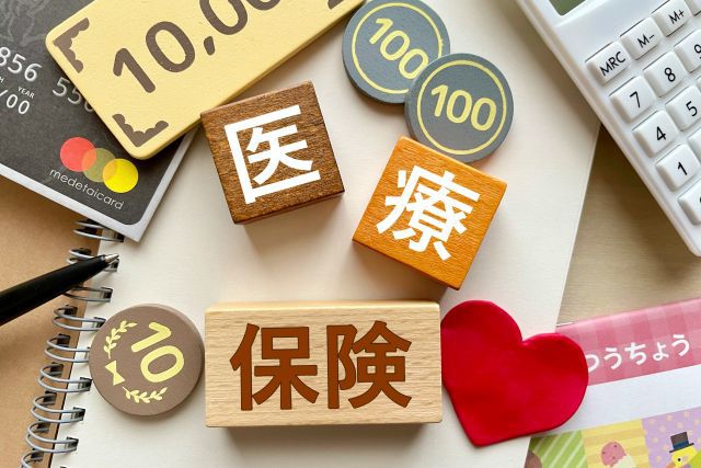 医療保険と書かれたブロックとノートと電卓