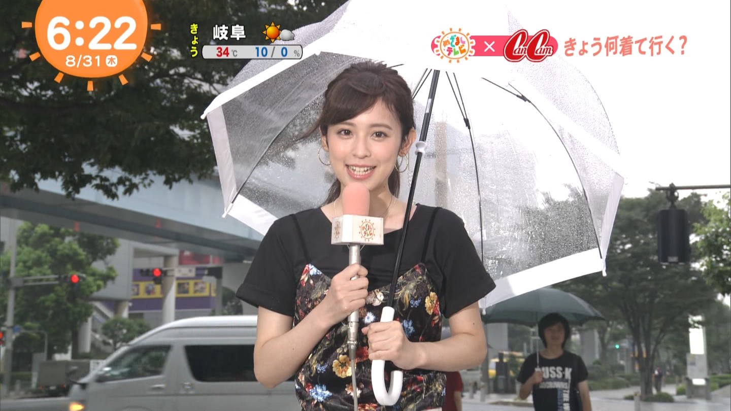 傘を持ってテレビ中継をしている女性