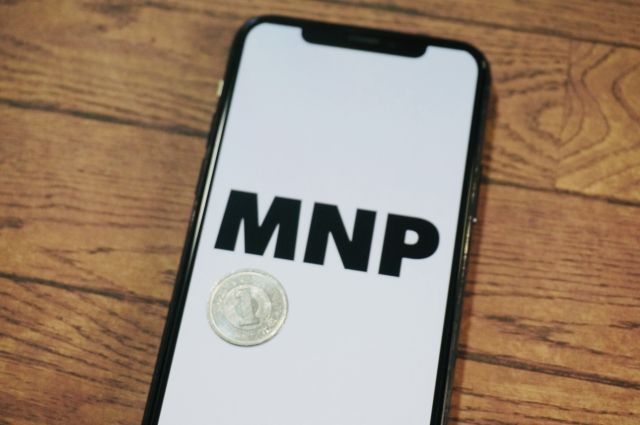 画面にMNPと表示されたスマホとその上に置かれたコイン
