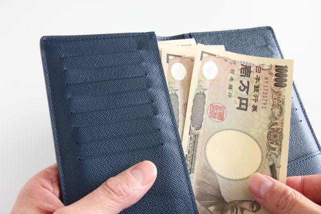 黒い長財布から1万円札を2枚出す人の手