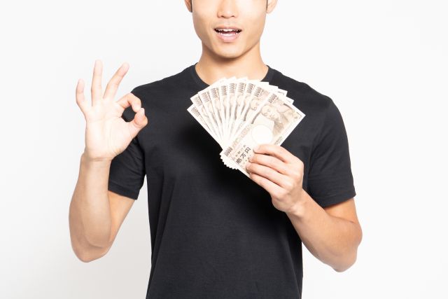 お金を持ってOKサインをする男性
