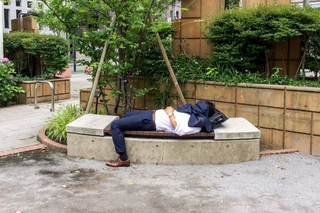 公園のベンチに寝てサボるサラリーマン
