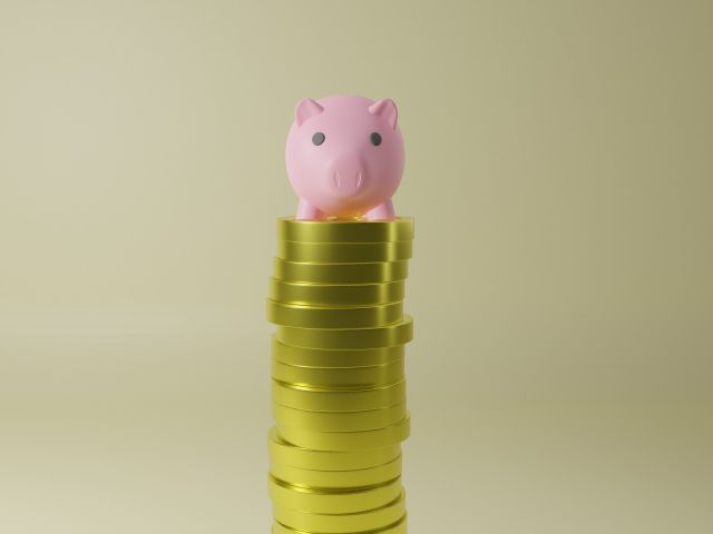 積み上げられたコインの上に乗った豚