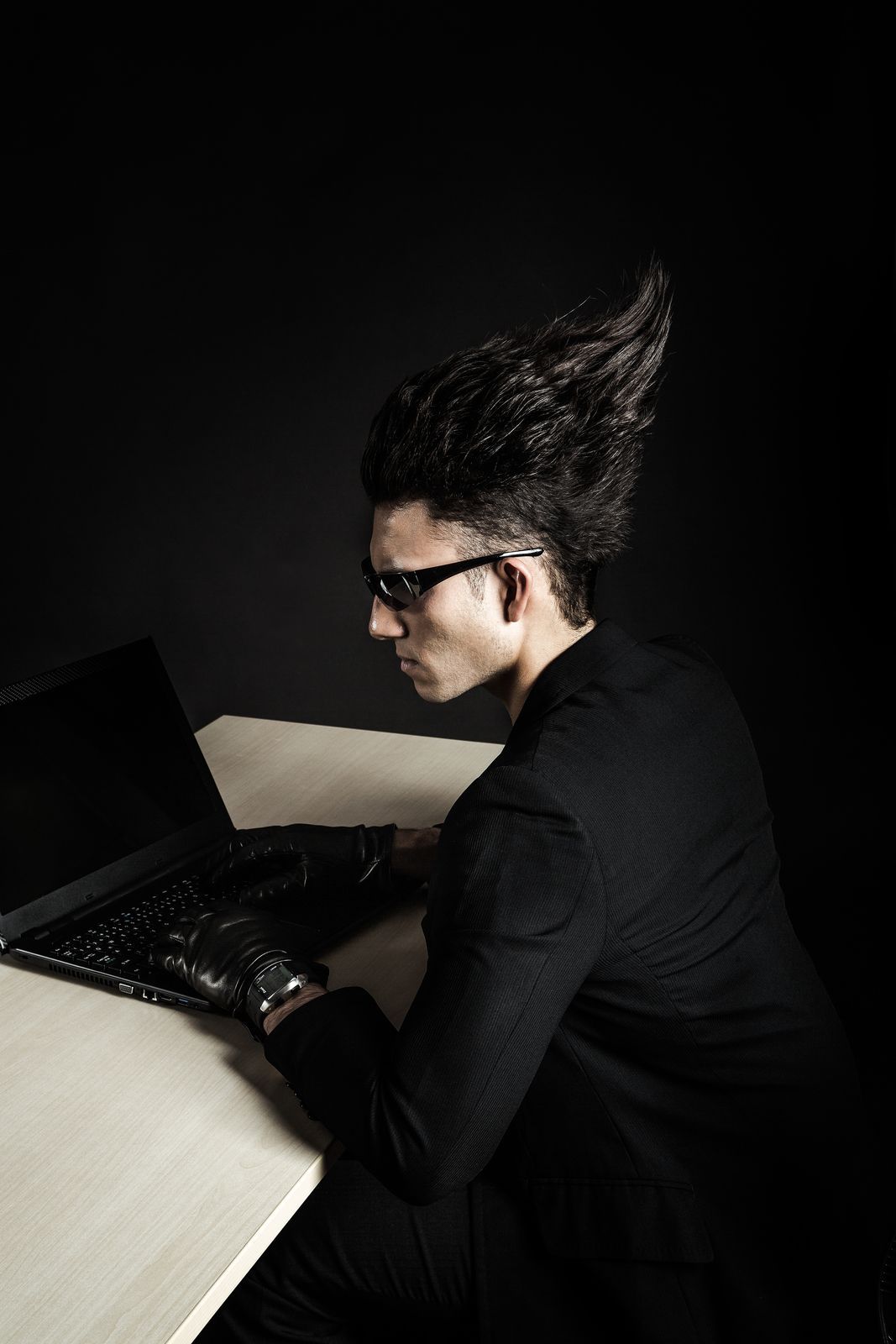 暗闇でパソコンを操作する奇抜な髪型のプログラマー