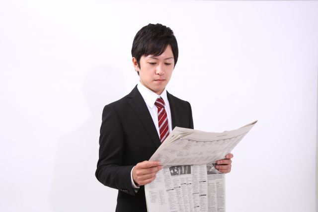 新聞を読むスーツを着た男性