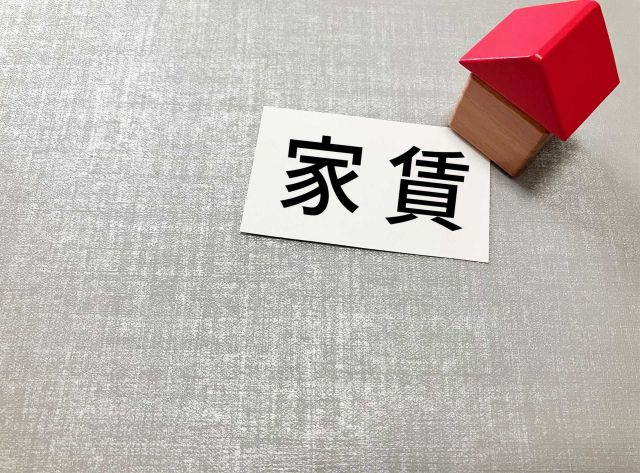 紙に書かれた家賃の文字と家の模型