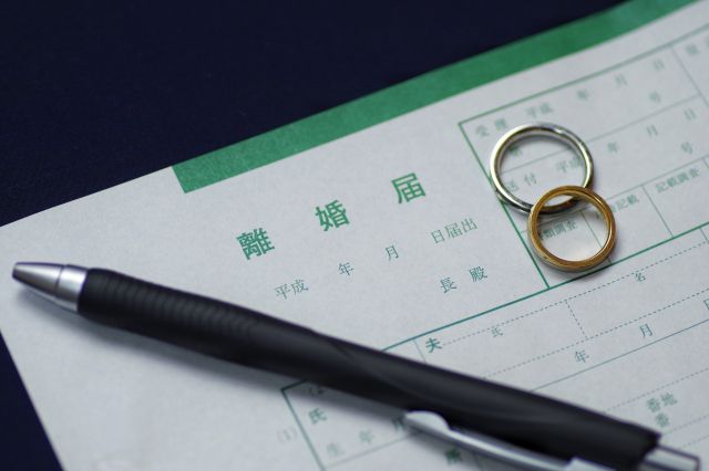 離婚届けの上に置かれた結婚指輪とボールペン