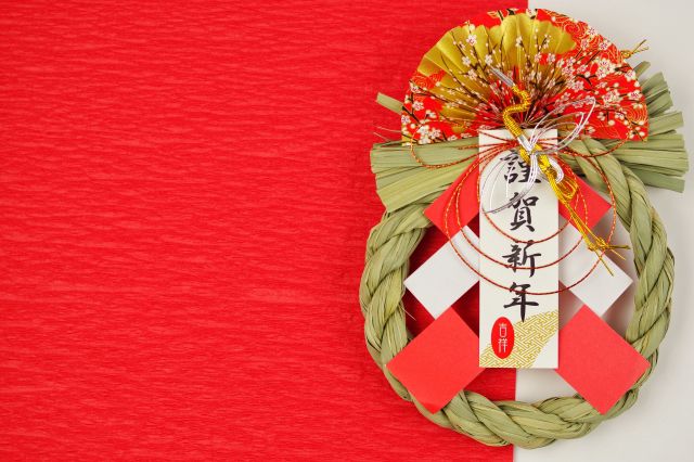 赤い和紙の上に置かれた謹賀新年のしめ縄