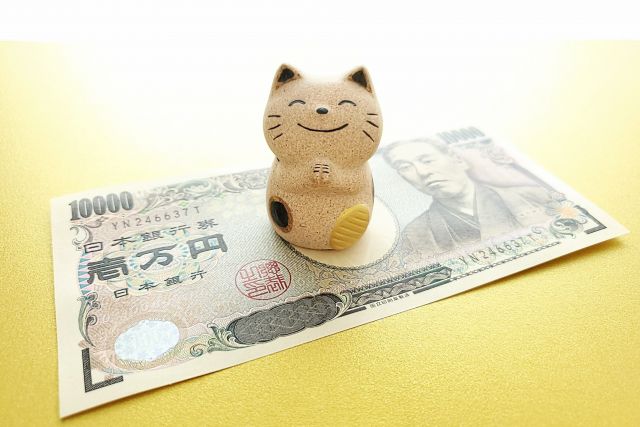 1万円札の上に置かれた招き猫