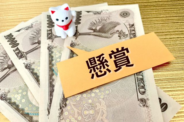 お金の上に置かれた懸賞と書かれた紙と猫の置物