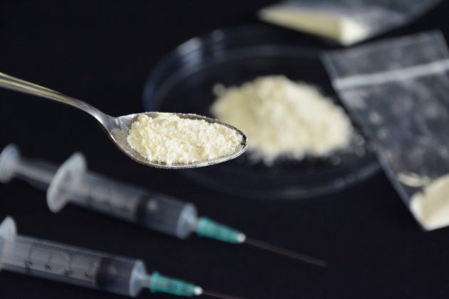 スプーンに乗せた白い粉と複数の注射器