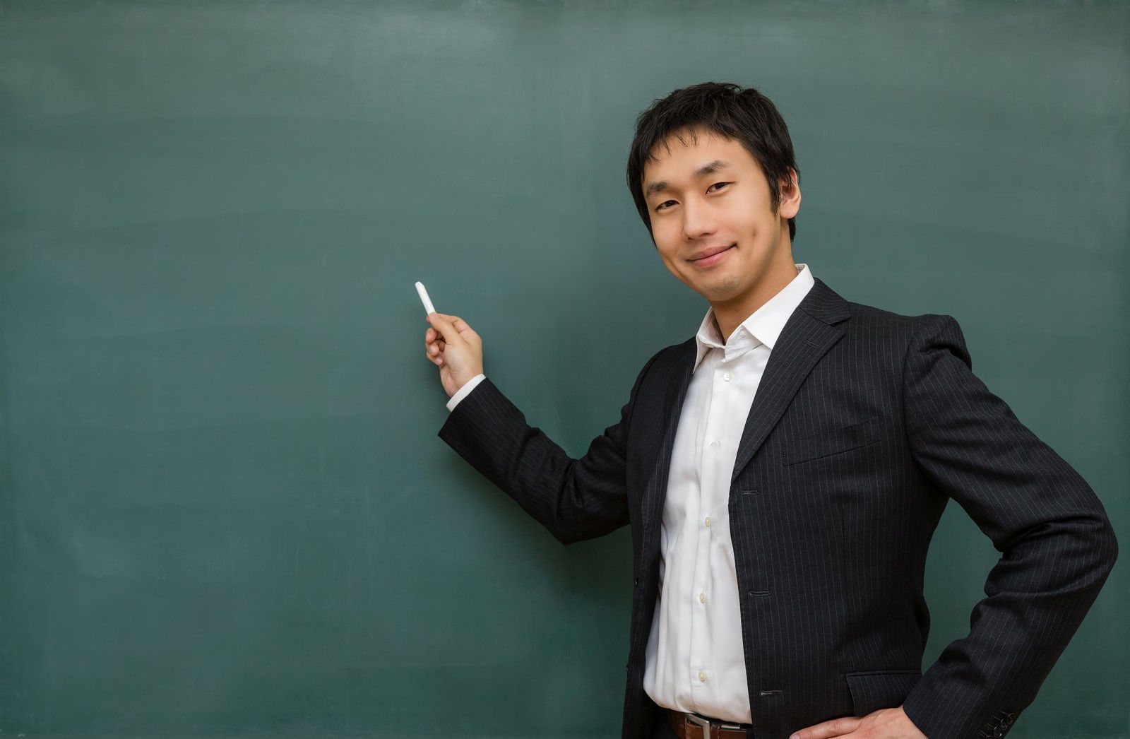 笑顔で黒板の前に立つ教師