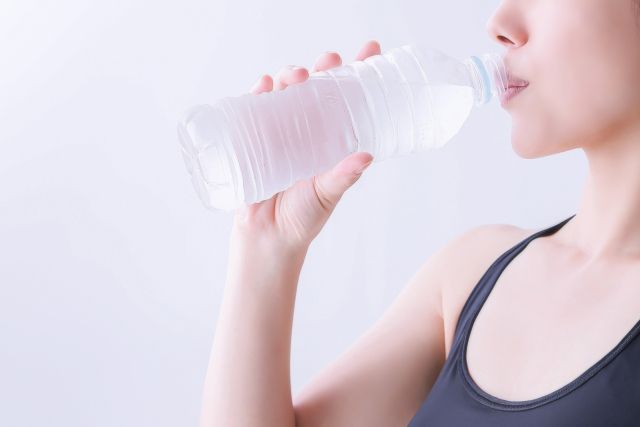 ペットボトルで水を飲む女性