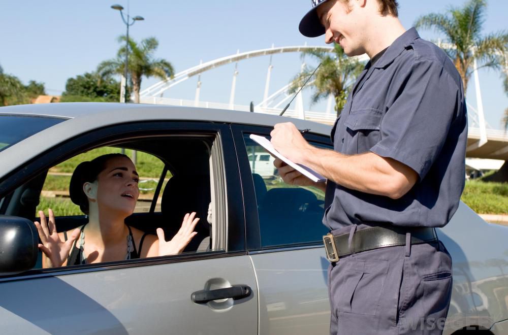 違反切符をきる男性警官と許しを乞う女性ドライバー