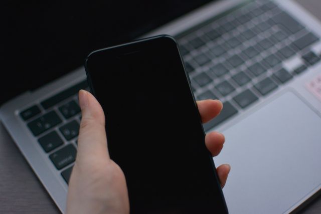 パソコンの前でスマホを持つ人