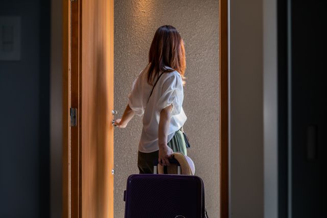 荷物を持って家を出る女性